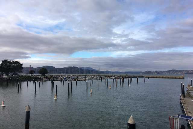 A cloudy day at a marina with multiple boats docked and floating on the water.