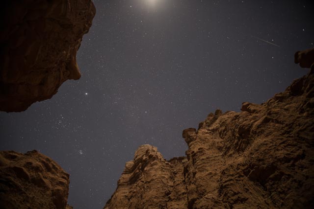 A night sky filled with stars visible through a natural rock formation.