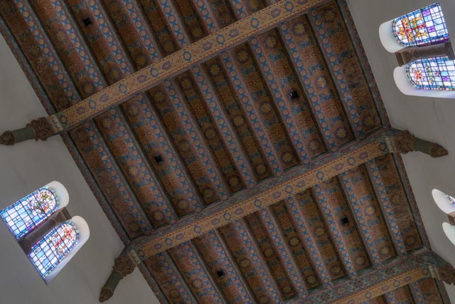 An ornate ceiling features intricate gold and blue patterns on wooden beams.