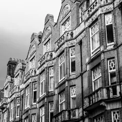A row of ornate brick townhouses with decorative gables, bay windows, and stone carvings, captured from a low angle.