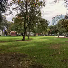 A park with a large lawn and trees on a cloudy day.