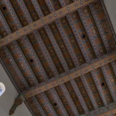 An ornate ceiling features intricate gold and blue patterns on wooden beams.