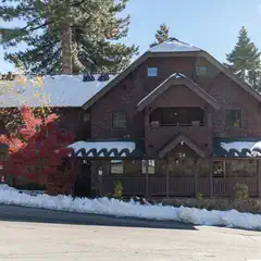 A two-story building with brown shingle siding and a covered porch, featuring a dark roof and several windows.
