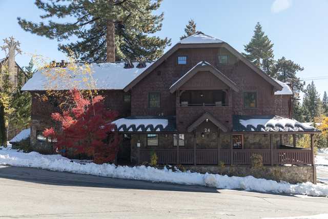 A two-story building with brown shingle siding and a covered porch, featuring a dark roof and several windows.