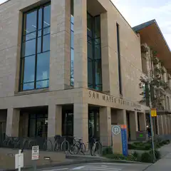 A modern library building with large windows and a sign that reads "San Mateo Public Library".