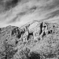 A rocky outcropping rises from a hillside covered in scrubby vegetation.