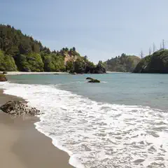 A sandy beach curves toward a cove with green hills on either side.