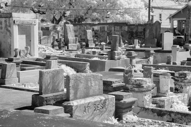 A cemetery contains numerous headstones and grave markers, some of which are weathered and worn.