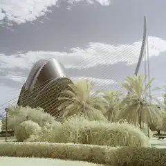 A futuristic bridge with a large dome structure and palm trees around it.