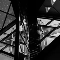 A geometric glass structure with triangular panels and dark metal framework.