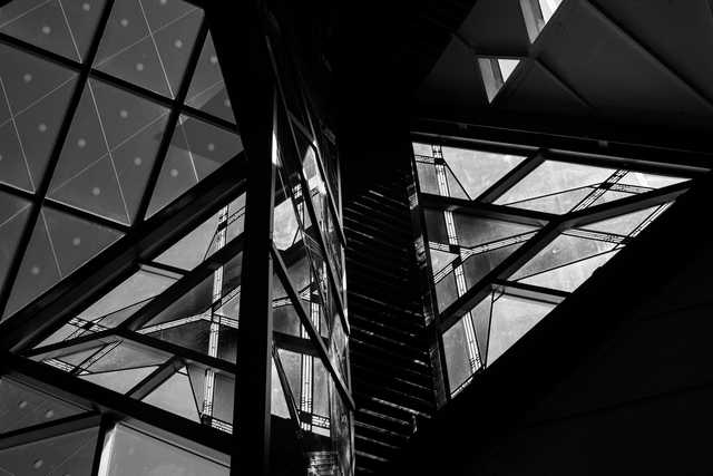 A geometric glass structure with triangular panels and dark metal framework.