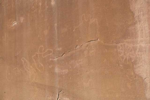 A light-colored rock face features several abstract shapes etched into its surface.