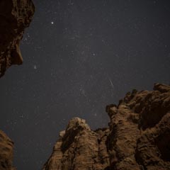 An opening in rocky terrain, showing a starlit night sky.