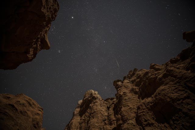An opening in rocky terrain, showing a starlit night sky.