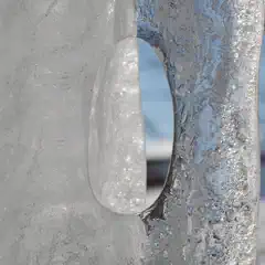 An oval-shaped hole is visible in a block of ice.