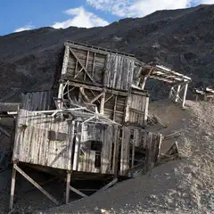 An old wooden structure leans precariously on a hillside.