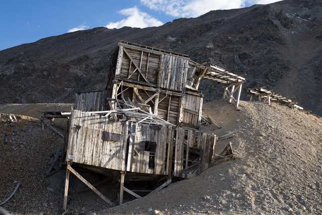 An old wooden structure leans precariously on a hillside.