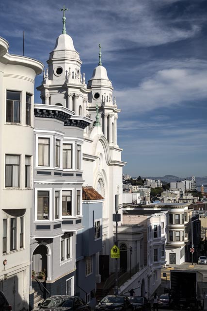 A white church with two towers overlooking a city.