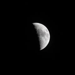 An illuminated half-moon with craters and ridges is visible against a black background.