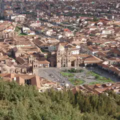 A cityscape with a large plaza surrounded by historic buildings featuring red-tiled roofs, viewed from an elevated perspective.