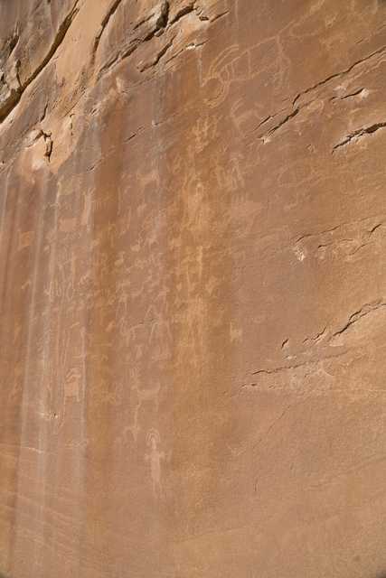 A large sandstone rock face features ancient petroglyphs etched into its surface.