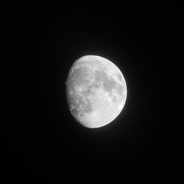 An almost full moon is shown against a black background.