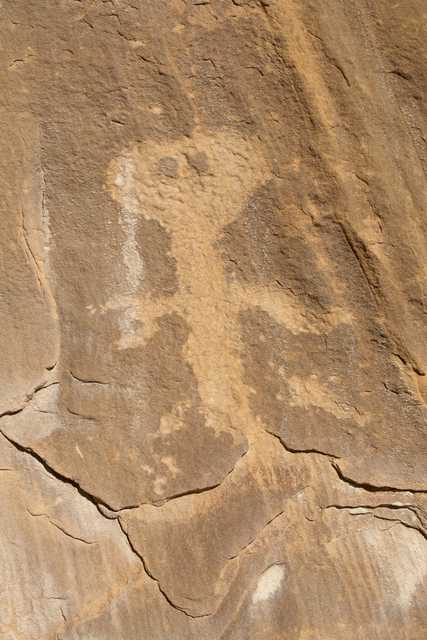 A rock face with a large, ancient petroglyph carved into it, showcasing an abstract human-like figure.