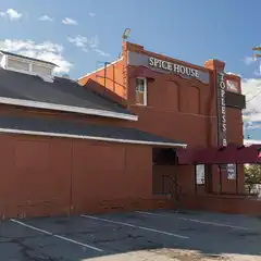 An old red brick building with a sign that reads "Spice House" and a parking lot in front of it, under a partly cloudy sky.
