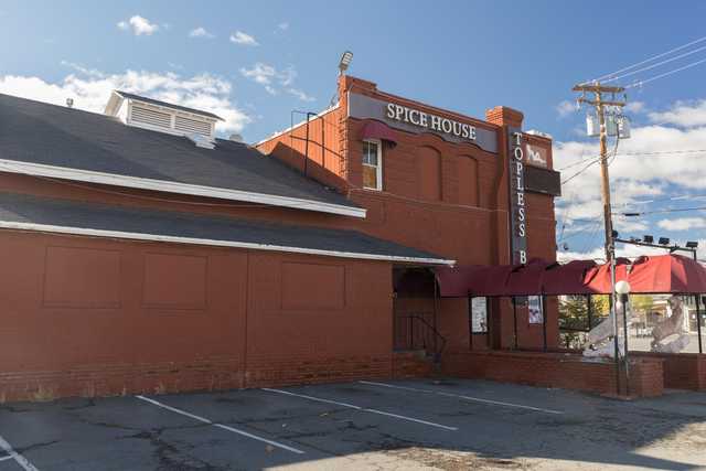 An old red brick building with a sign that reads "Spice House" and a parking lot in front of it, under a partly cloudy sky.
