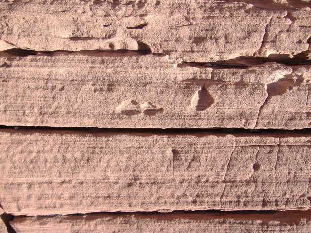 A weathered red rock formation with parallel cracks and crevices.