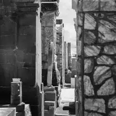 A narrow alleyway between stone walls with a glimpse of sky.
