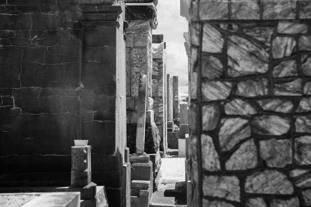 A narrow alleyway between stone walls with a glimpse of sky.