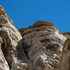 A rugged rock formation with layers of brown and tan sandstone under a clear blue sky.
