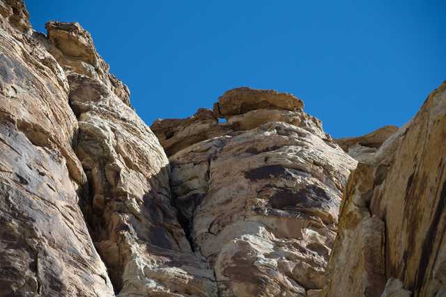 A rugged rock formation with layers of brown and tan sandstone under a clear blue sky.