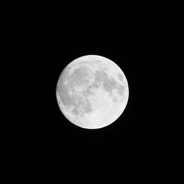 A full moon shining brightly against a dark night sky.