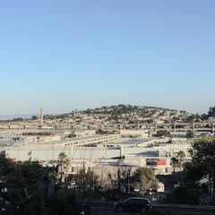 A large commercial district extends to a residential hillside under a clear blue sky.