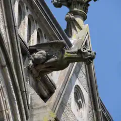 A stone gargoyle protrudes from a Gothic building facade.