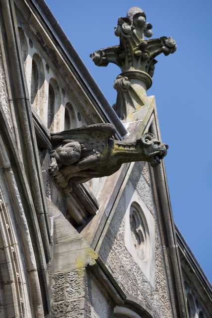 A stone gargoyle protrudes from a Gothic building facade.