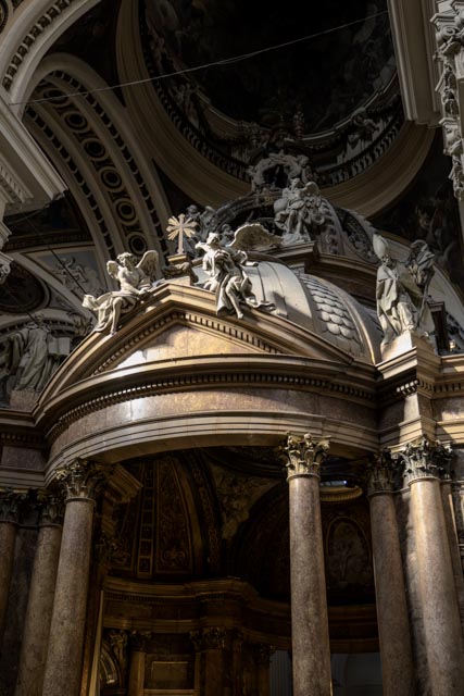 A grand church interior with a large golden altar featuring intricate carvings and statues, illuminated by natural light streaming through windows.