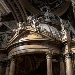 A grand church interior with a large golden altar featuring intricate carvings and statues, illuminated by natural light streaming through windows.