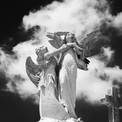 A statue of two angels is prominently displayed against a backdrop of clouds.
