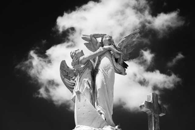 A statue of two angels is prominently displayed against a backdrop of clouds.