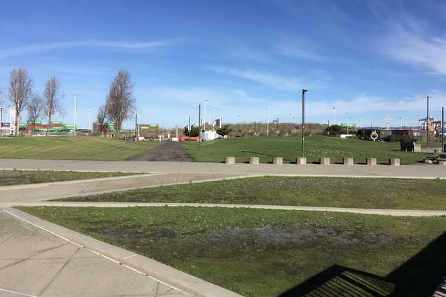 An asphalt path runs through a grassy area with concrete barriers along its edges.