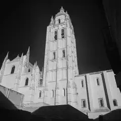 A tall bell tower rises above a stone building with pointed spires and arched windows.