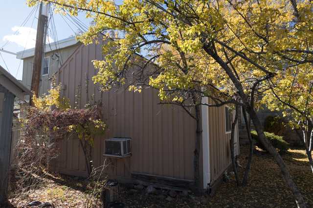 A small brown building with white trim is surrounded by trees with yellow leaves.