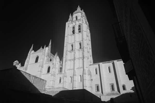 A tall bell tower rises above a stone building with pointed spires and arched windows.