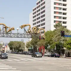 An ornate gateway depicting golden dragons spans a city street lined with vehicles and multi-story buildings.