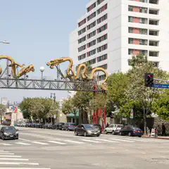 An ornate gateway depicting golden dragons spans a city street lined with vehicles and multi-story buildings.