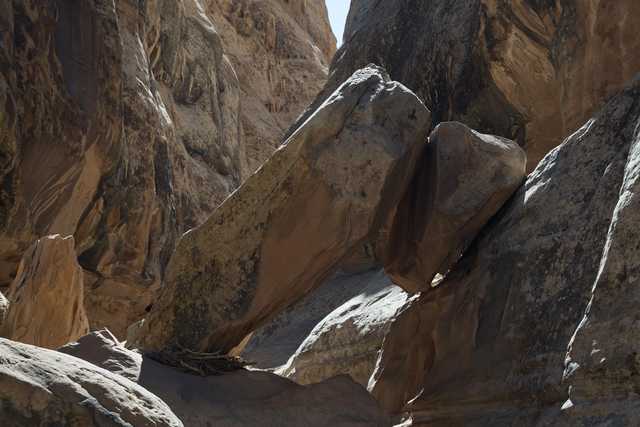 A narrow canyon contains large, angled rock formations and shadowed walls.