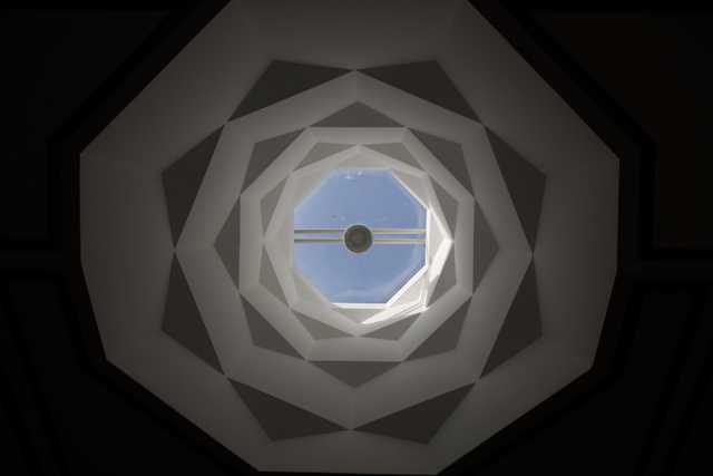 A view looking up through a series of nested octagonal openings toward a central skylight.